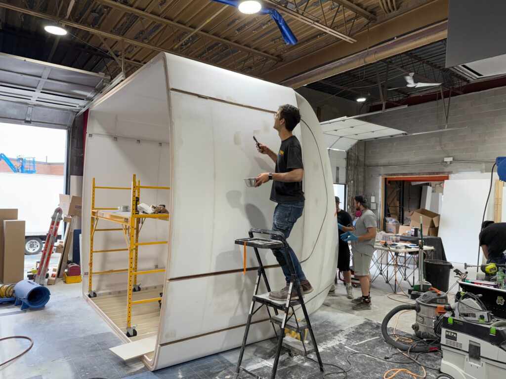 Fabricator applying a surface finish to a curved custom trade show booth in the workshop
